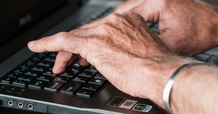 Manos de anciano en teclado. Facebook